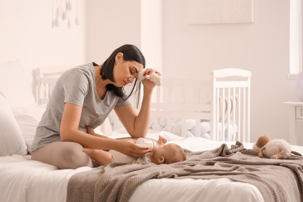 Przygnębiona kobieta karmi dziecko. Depresja poporodowa — jak się objawia