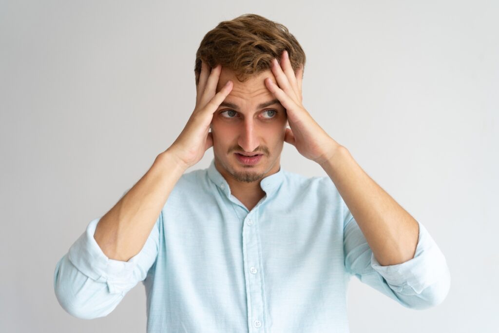 Przerażony czymś mężczyzna z dłońmi przy skroniach